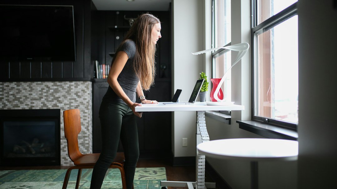 Person using a compact treadmill at a standing desk in a bright home office